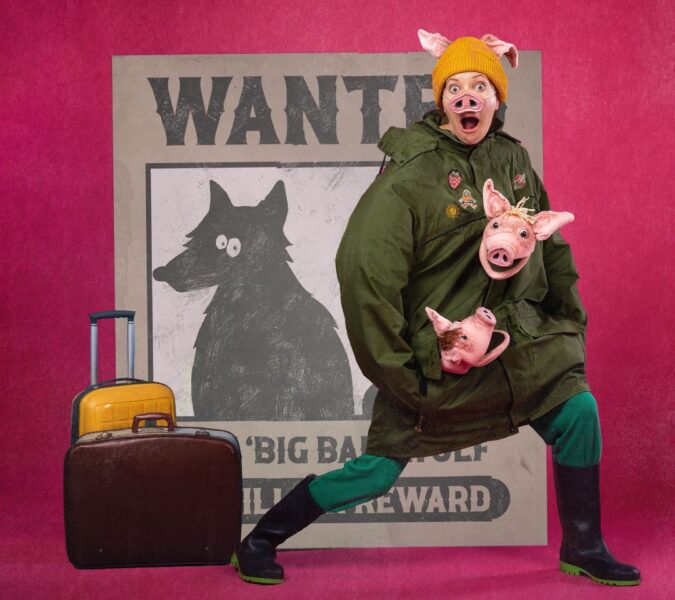 A person with pig ears and nose and a toy pig head sticking out of their green coat. There are two suitcases at the side of them and a wanted poster behind them with a picture of a wolf.