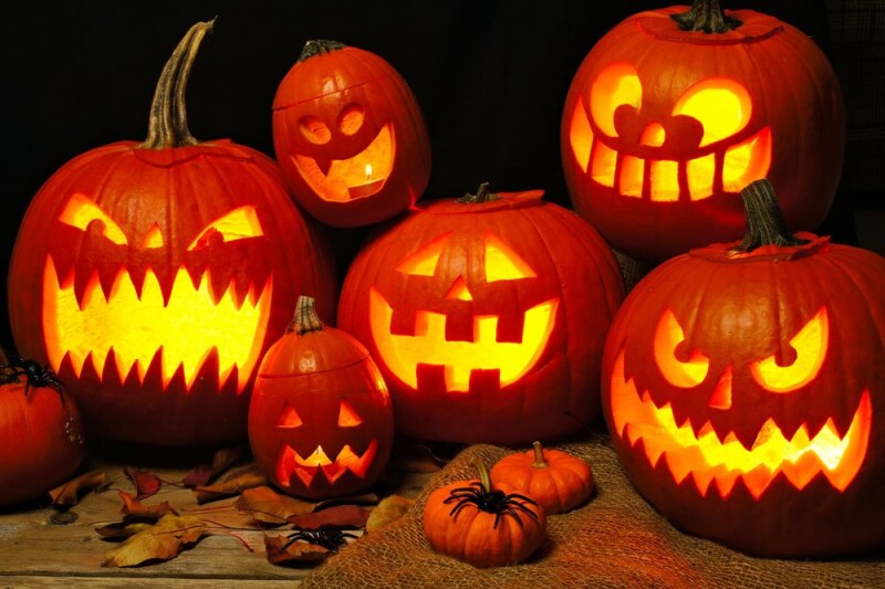 A group of glowing orange pumpkins with different facial expressions carved into them.