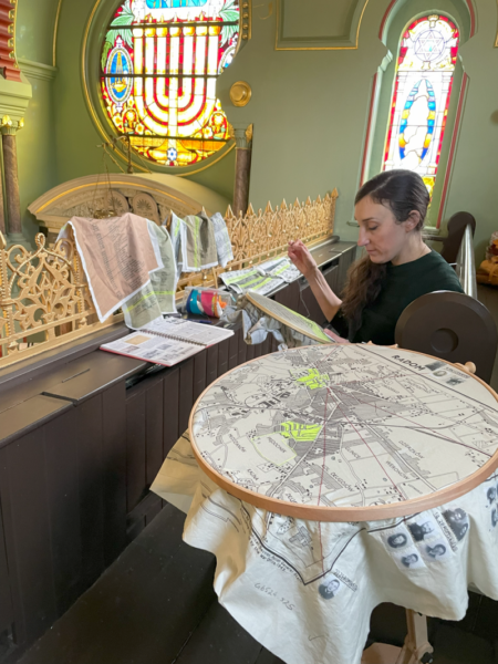 Laura Nathan working on an embroidery piece in Manchester Jewish Museum's historic synagogue, 2024.