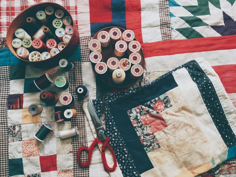 An assortment of craft materials including fabrics, scissors and colourful rolls of cotton.