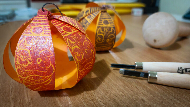 Two hand-crafted Chinese lanterns and some crafting tools on a table.