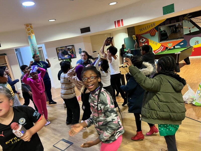 A group of young people doing a range of different activities in a community room.