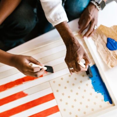 A close up of two sets of hands painting a flag.