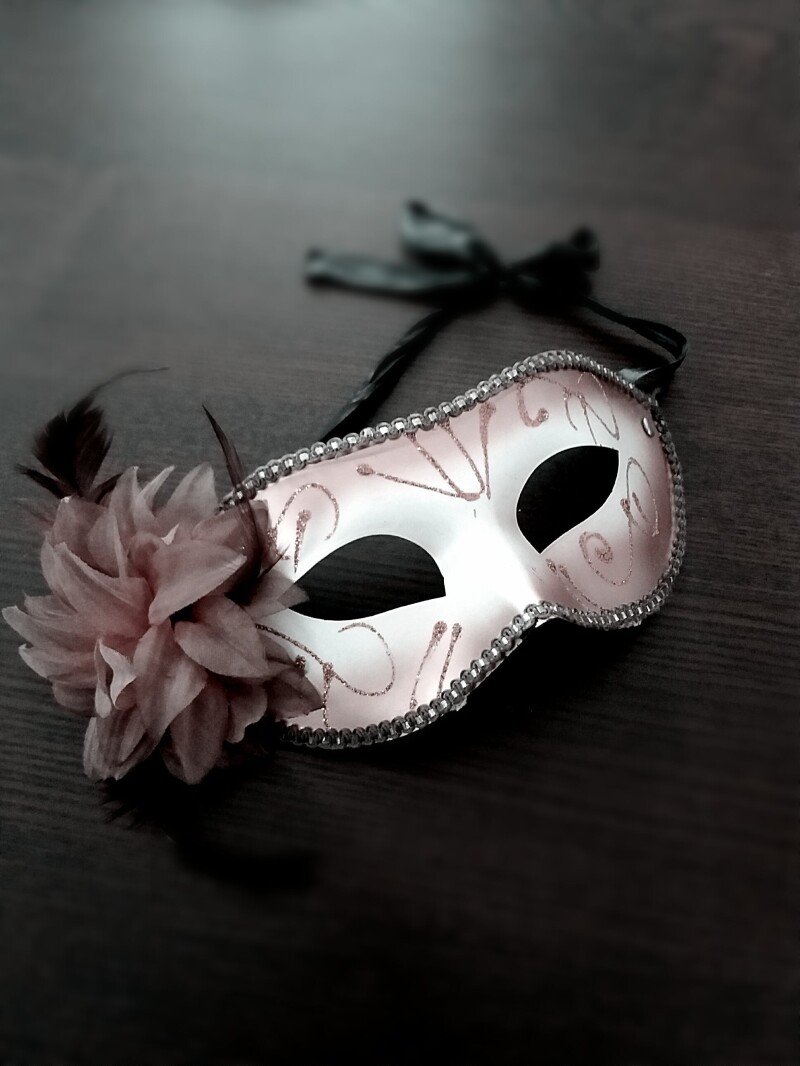 A white Venetian theatre mask with a flower attached.