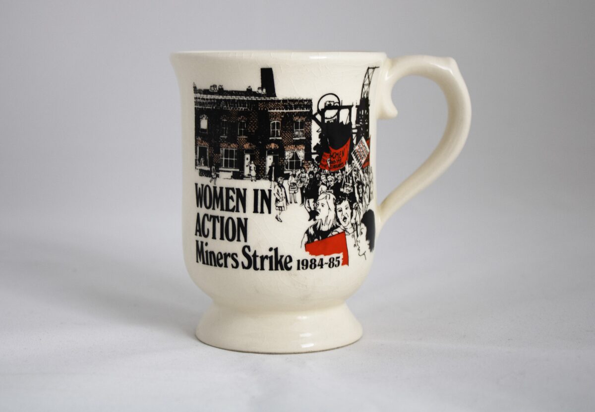 A mug with an illustration of a march and a colliery. Text reads: Women in Action Miners Strike 1984-85