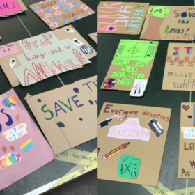 Colourful placards with messages which include Love the World and Girls can play football too.