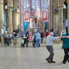 A couple dance in front of a crowd of people at a music cafe in Gorton Monastery.