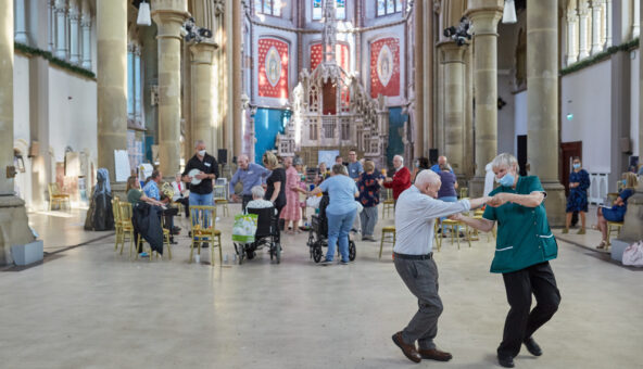 A couple dance in front of a crowd of people at a music cafe in Gorton Monastery.