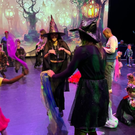 A group of young people in Halloween fancy dress playing party games.