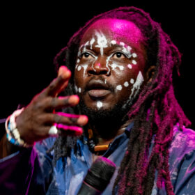 Headshot of singer holding a microphone and dancing.