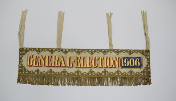 A banner with gold fringing, embroidery, and lettering reading: 'General Election 1906'.