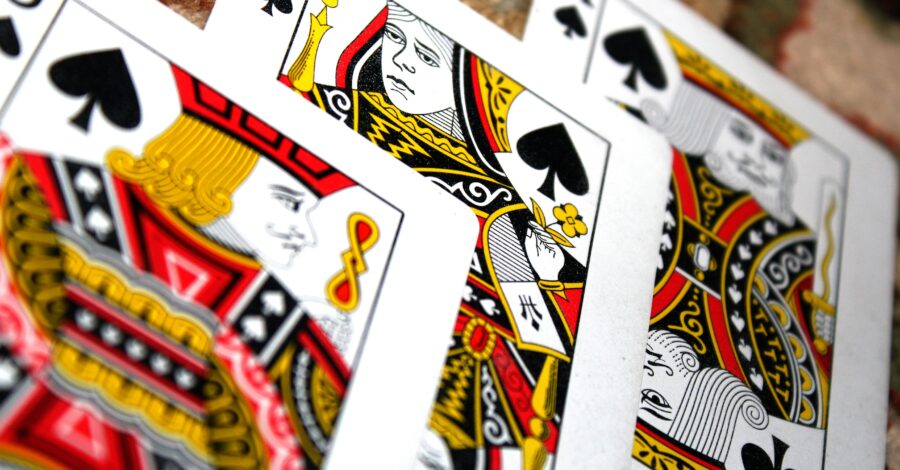 A King, Jack and Queen of Spades playing cards on a table.