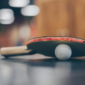 A table tennis bat and a small white ball placed on a table.