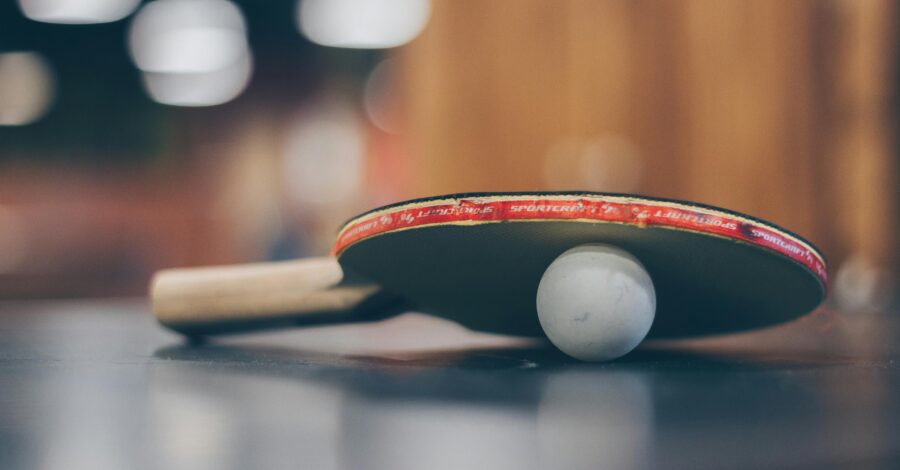 A table tennis bat and a small white ball placed on a table.