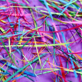 Strips of multi-coloured paper on a purple table cloth.