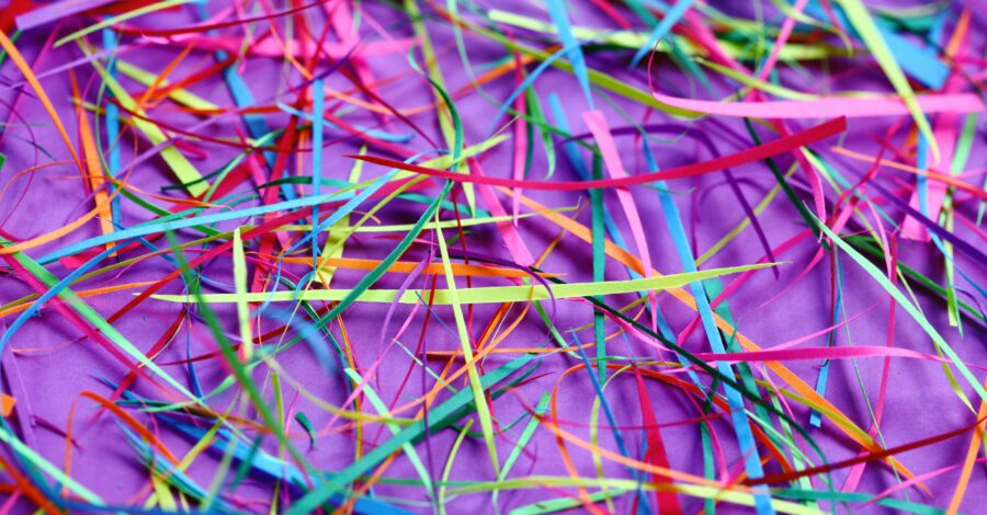 Strips of multi-coloured paper on a purple table cloth.