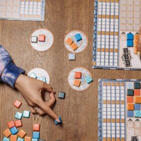 Two people playing a board game with orange and blue counters.