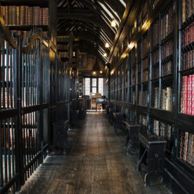 A wood panelled corridor with lined with shelves of antique books