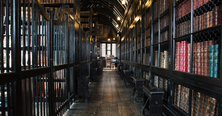 A wood panelled corridor with lined with shelves of antique books