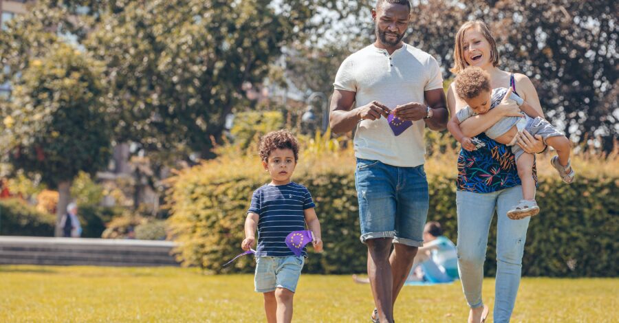 A family of four walking across a grassy field in a park.