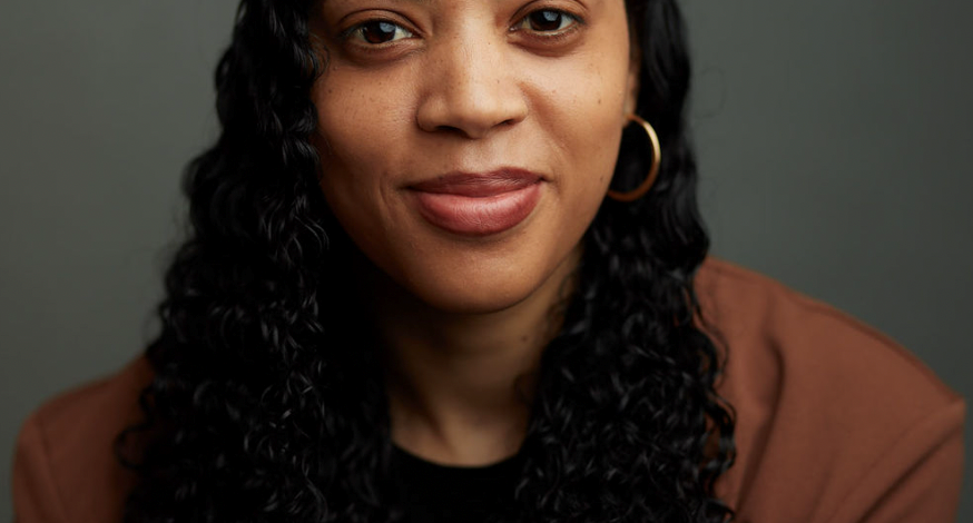 The head and shoulders of author Kimberley Whittam. She wears an orange top and has long black hair.