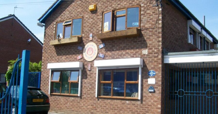 The exterior of the Woodhouse Park Family Centre with brown bricks, a pitched roof and four windows.