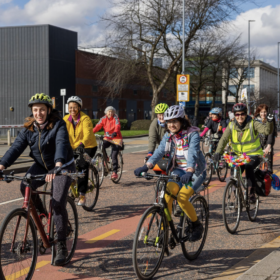 A group of people riding their bikes down a road on a bright day.