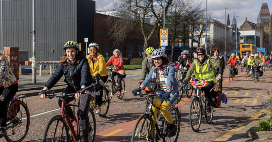 A group of people riding their bikes down a road on a bright day.