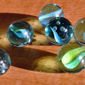 Six glass marbles on top of a wooden table.