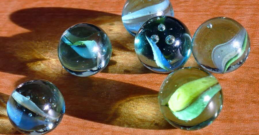 Six glass marbles on top of a wooden table.