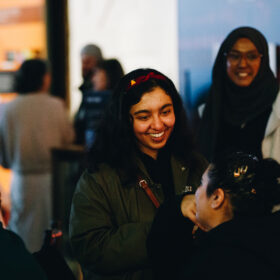 A crowd of people at an event, they are smiling.