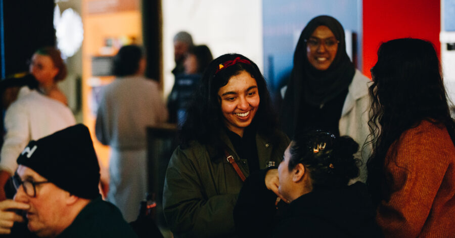 A crowd of people at an event, they are smiling.