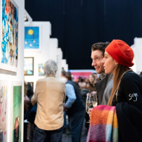 A couple of people looking at a picture on the wall at an art exhibition.