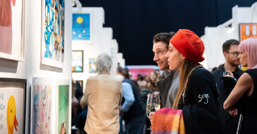 A couple of people looking at a picture on the wall at an art exhibition.