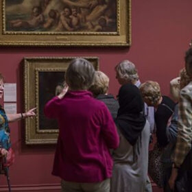 A group of people looking at framed artwork on the walls of a gallery.