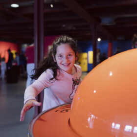 A young girl smiling playing in the Experiment gallery