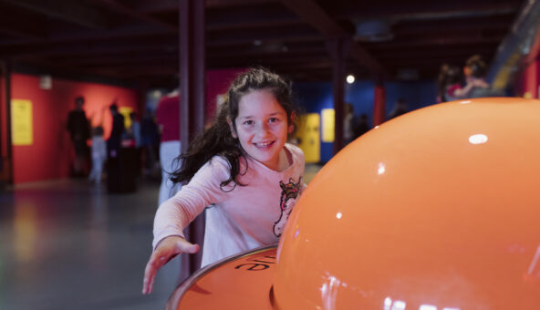 A young girl smiling playing in the Experiment gallery