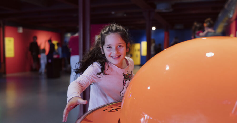 A young girl smiling playing in the Experiment gallery