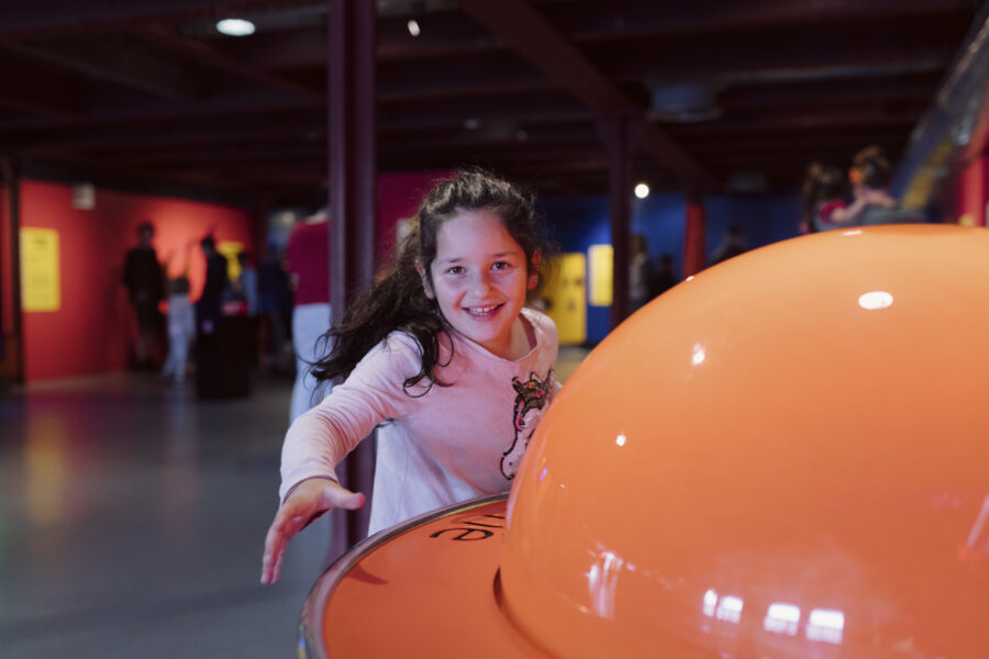 A young girl smiling playing in the Experiment gallery