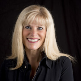 A picture of the head and shoulders of author Caroline England. She wears a black top, has light blonde hair and is smiling.