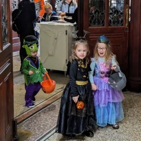 Three children dressed in fancy dress. One is a fairy, one is a witch and a smaller child is dressed as Frankenstein.