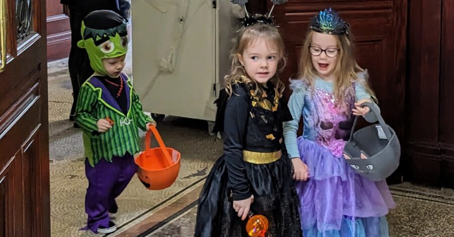 Three children dressed in fancy dress. One is a fairy, one is a witch and a smaller child is dressed as Frankenstein.