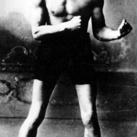 Black and white photo of Len Johnson in boxing attire and in a fighting stance.