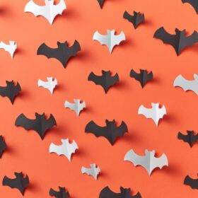 Black and white paper bats on an orange background.