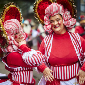 Two people in red and white fancy dress and wigs taking part in the Manchester Christmas Parade.