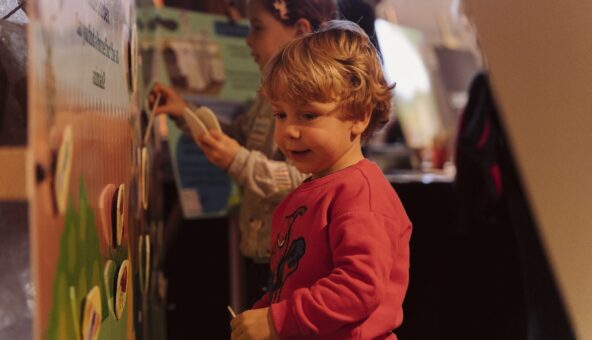 A small boy sticking illustrations to an interactive wall.