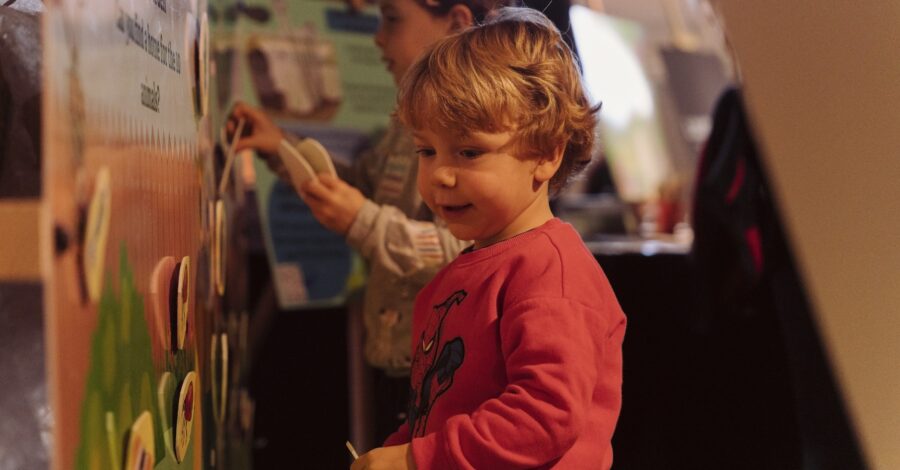 A small boy sticking illustrations to an interactive wall.