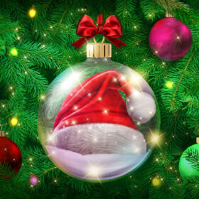 A giant glass bauble with a red and white Santa hat inside hanging from a Christmas tree.