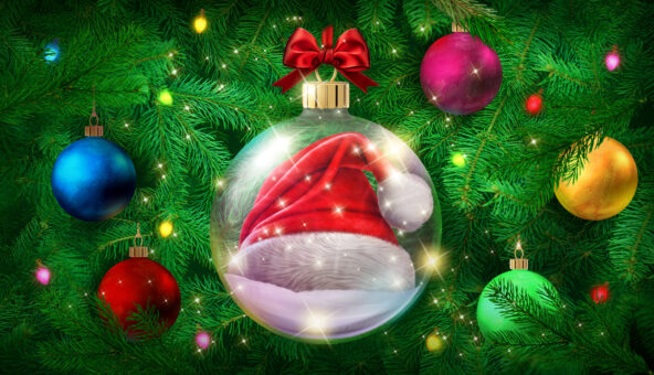 A giant glass bauble with a red and white Santa hat inside hanging from a Christmas tree.