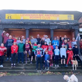 A crowd of people in christmas costumes stood outside Levenshulme Boxing Club before taking part on a Santa Run.